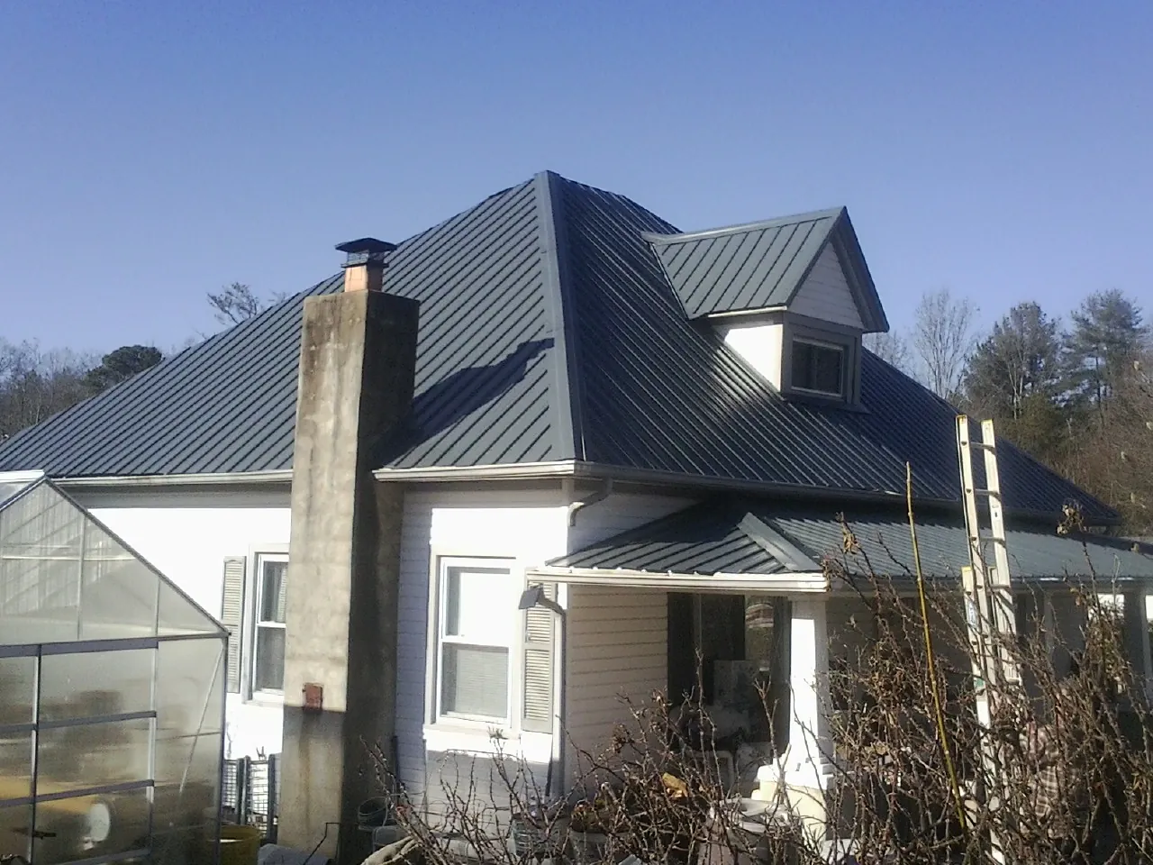 Dark blue standing seam metal roof on a white farmhouse with dormer — Slate & Tile Roof Repair by Roofing Brothers in Hickman